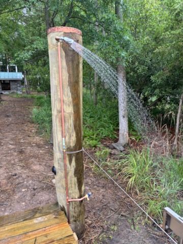 A wooden post with a shower head attached to it.