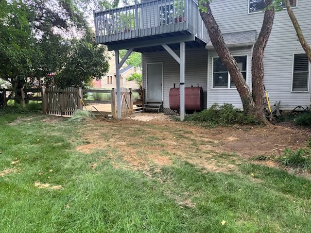 The backyard of a house with a deck and a fence.