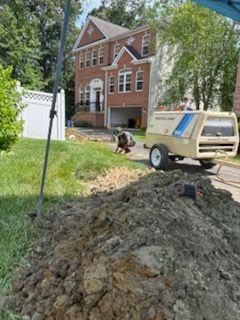 A man is digging in the dirt in front of a house.
