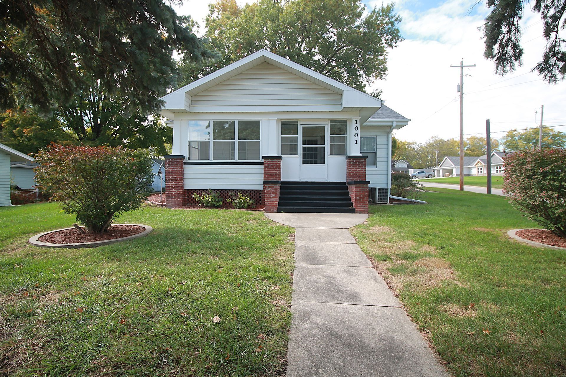 White bungalow house with a walkway, porch, and lawn.