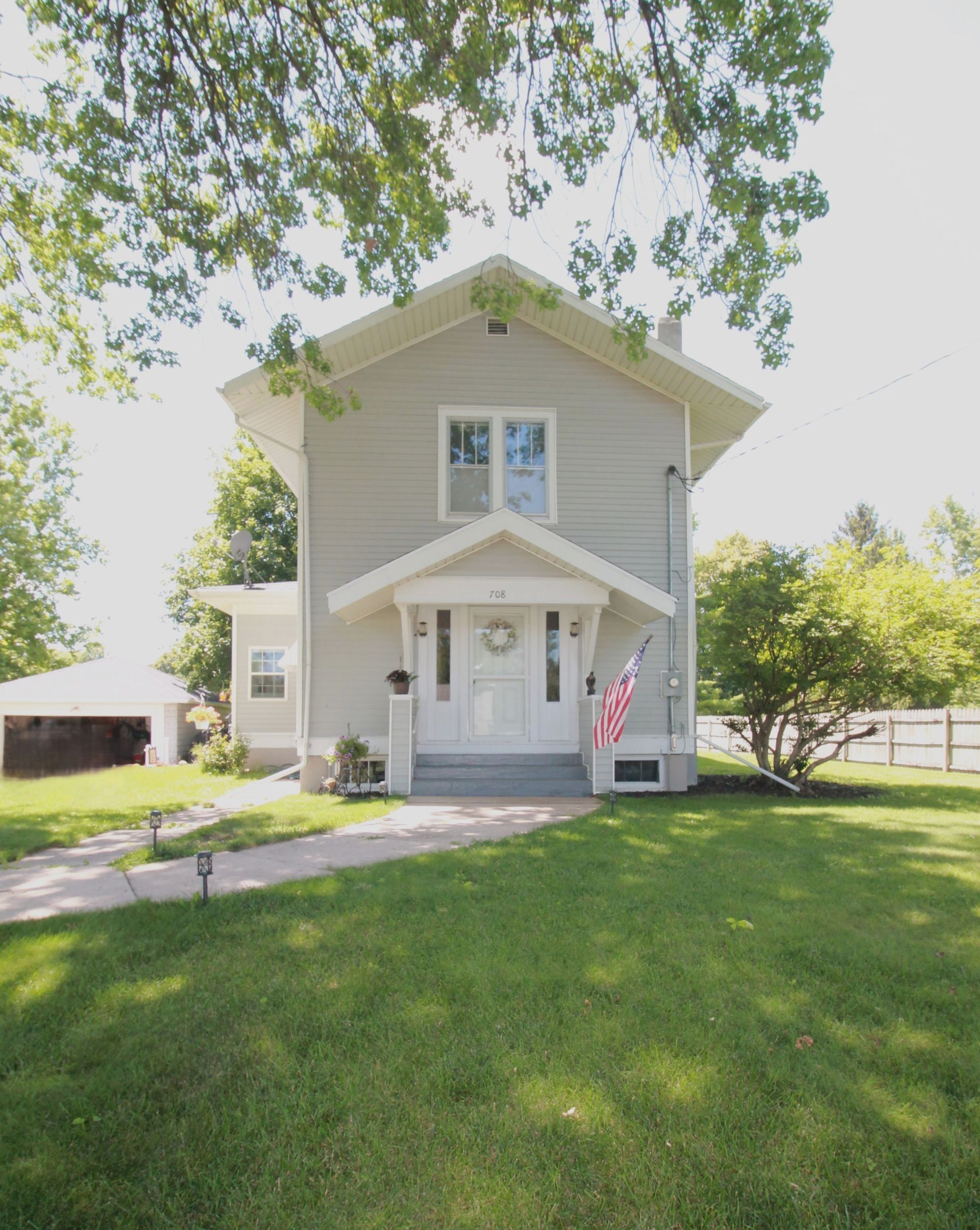 The front of a house with a flag on the porch