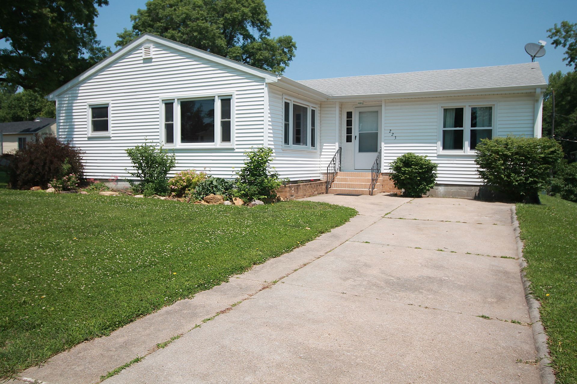 A white house with a concrete driveway leading to it