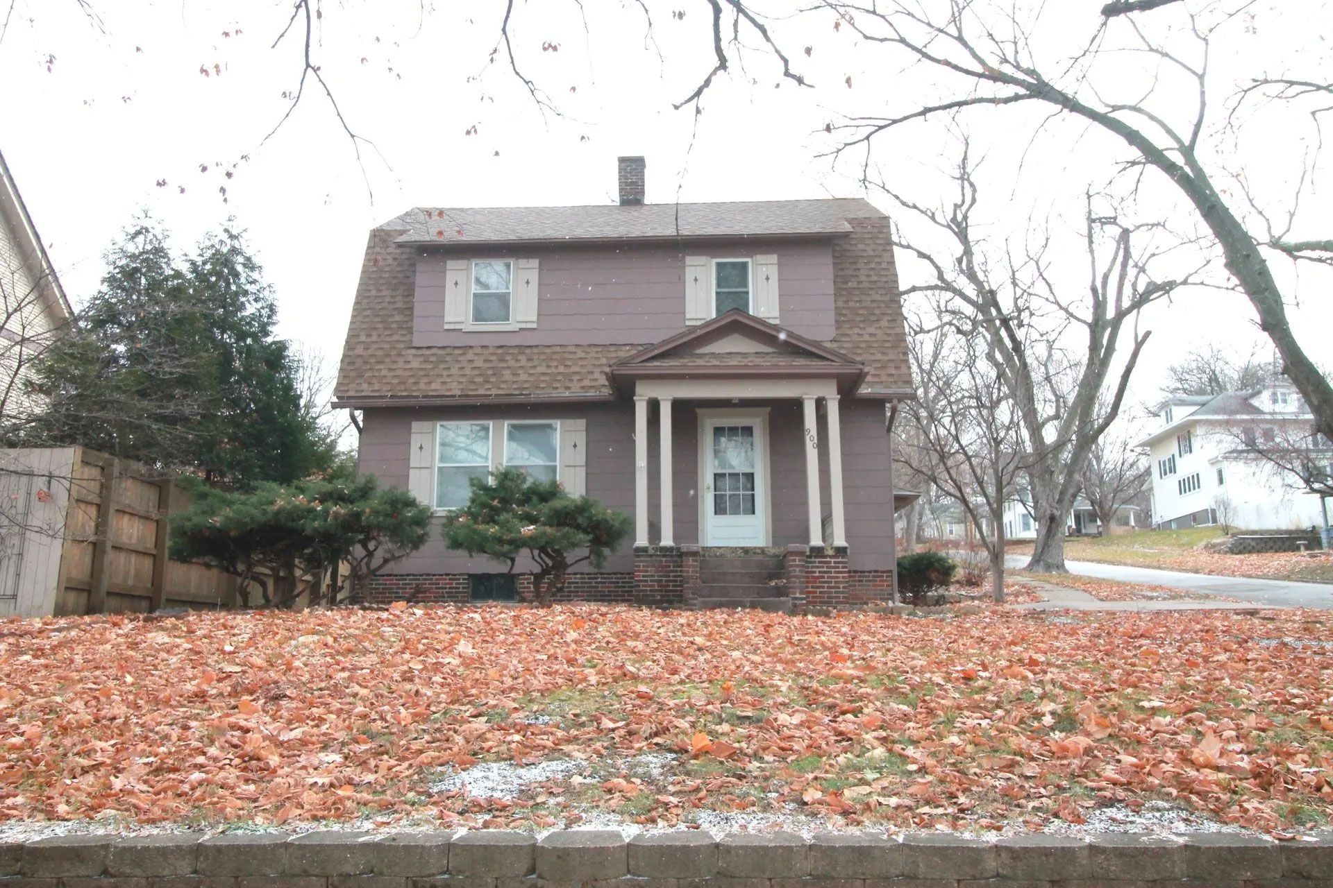 A house with a porch and a lot of leaves on the ground