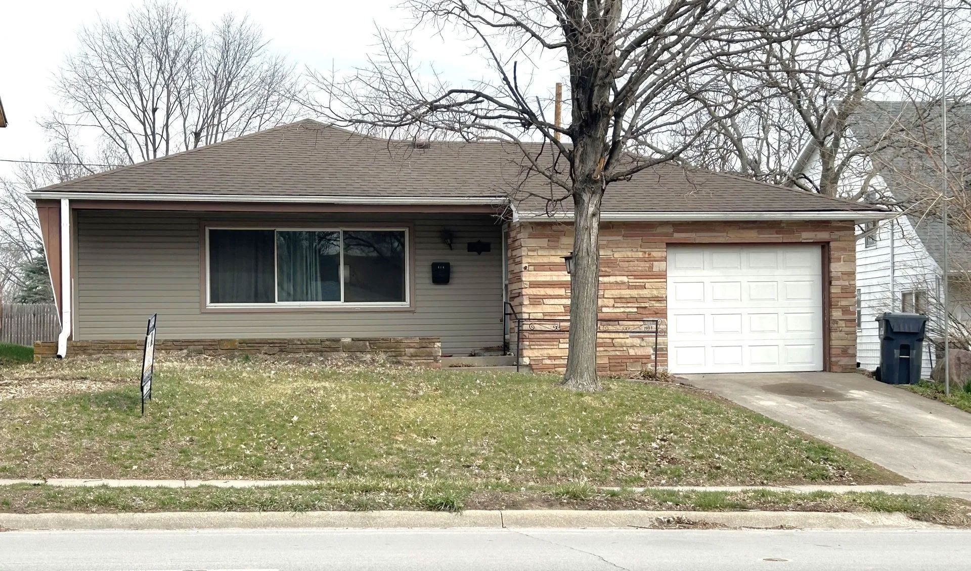 A house with a garage and a tree in front of it