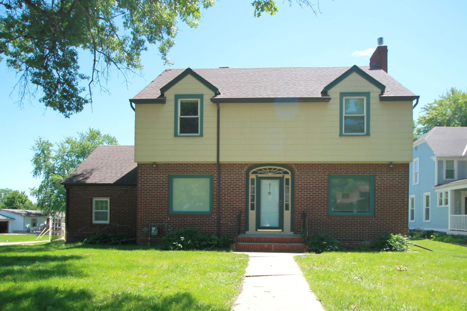 A brick house with a yellow facade and a walkway leading to it