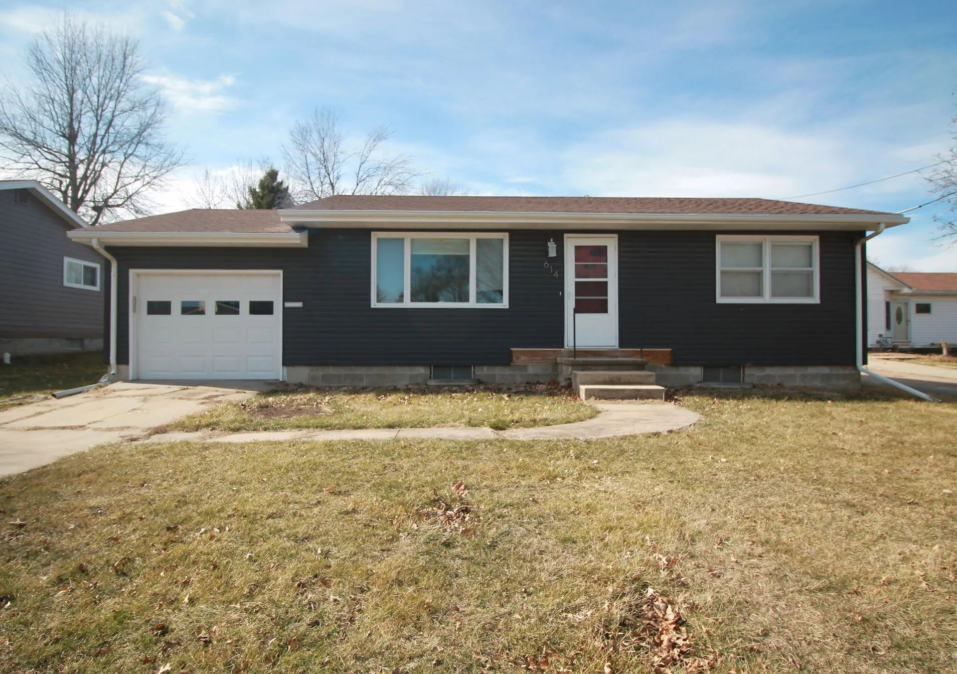 A small house with a garage and a lawn in front of it.