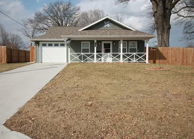 A small house with a porch and a garage is for sale.