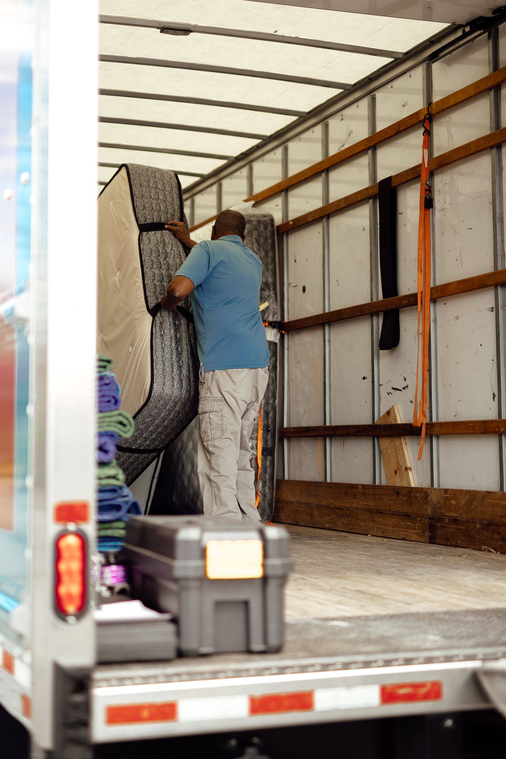 Person loading a large couch into a moving truck inside the cargo area.