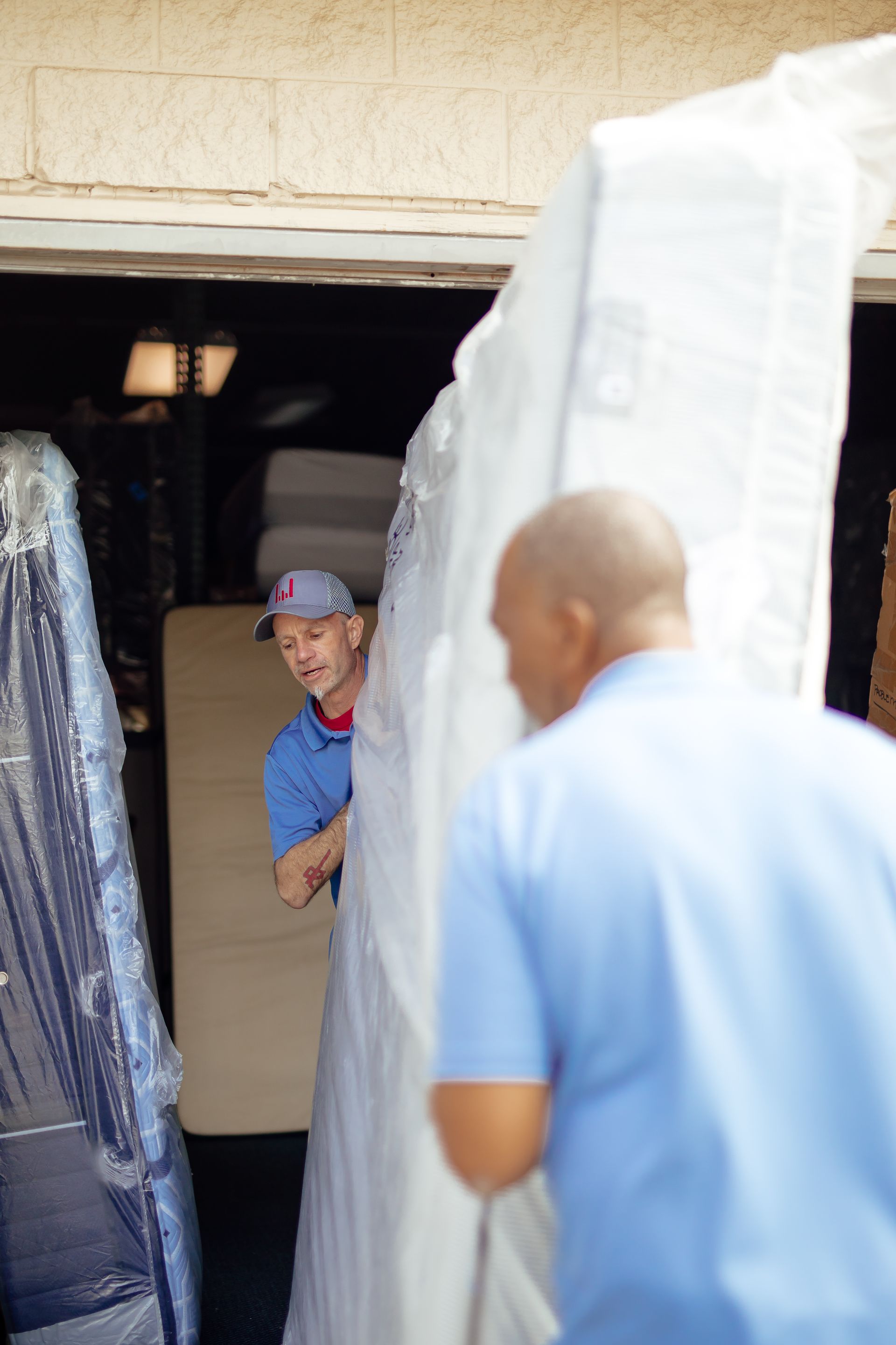Person in blue shirt stands at a doorway beside hanging white fabric, looking toward someone inside.