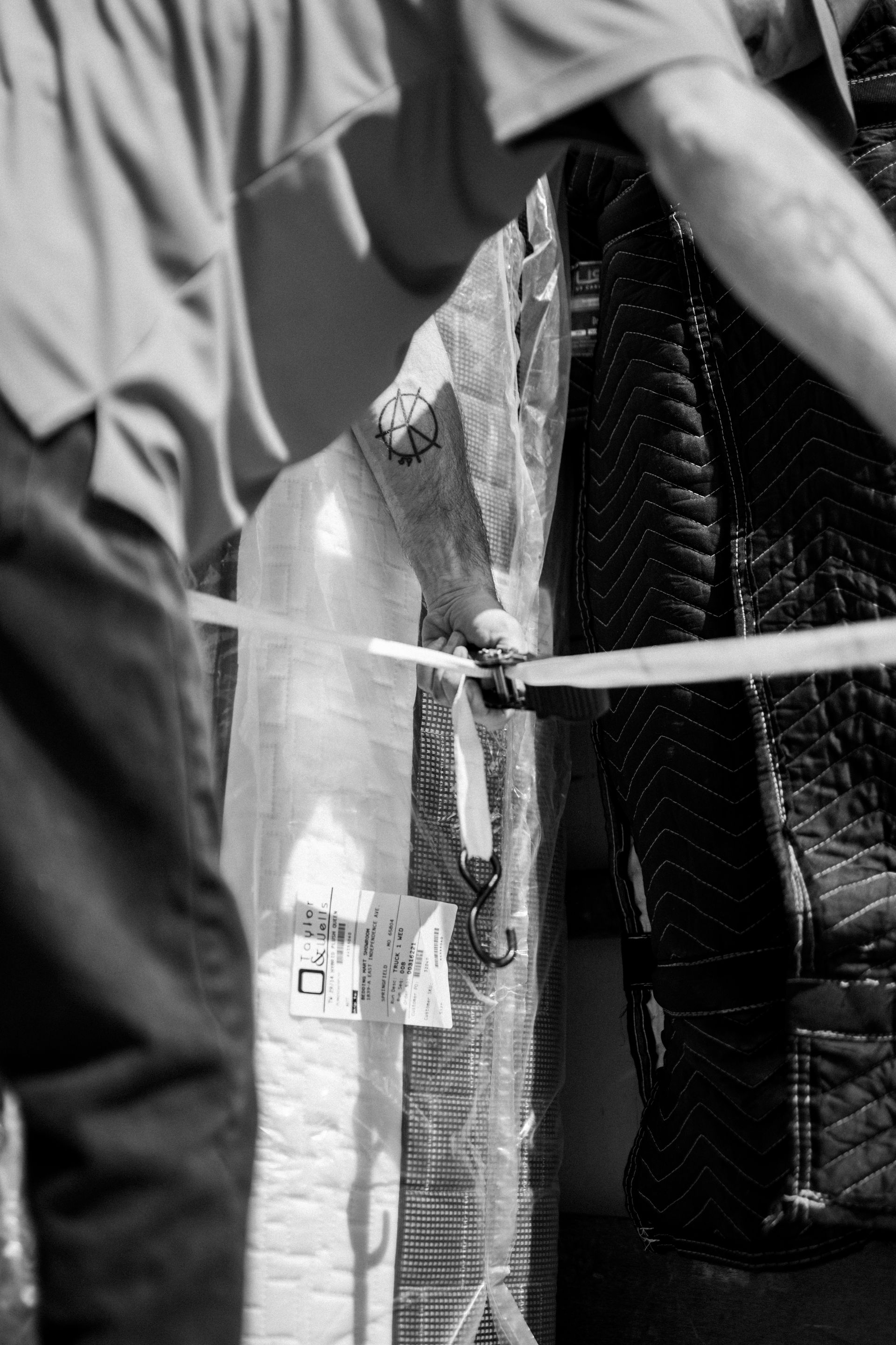 Person holding a clear umbrella in a rainy, crowded street scene with tape barriers and a brick wall.