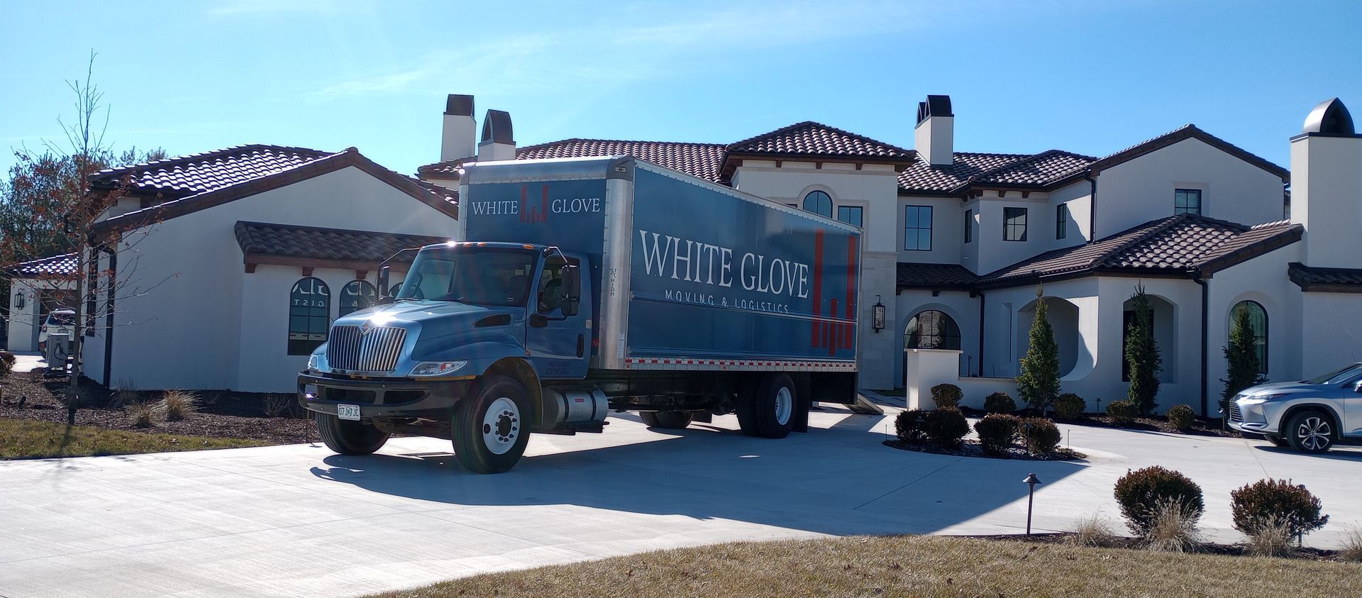 Blue truck parked in front of a white stucco building on a sunny street