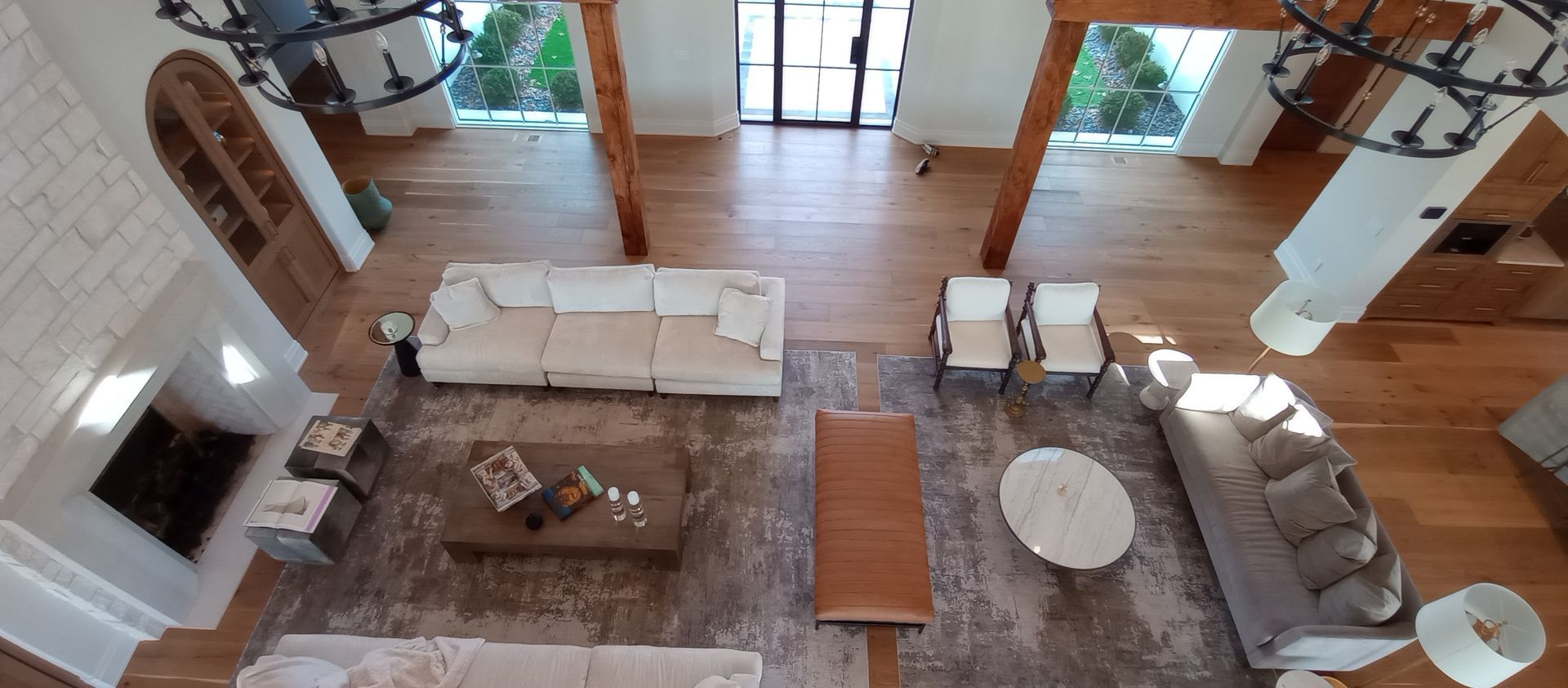 Open-concept living room with beige sectional sofa, rug, coffee table, fireplace, and wooden floors