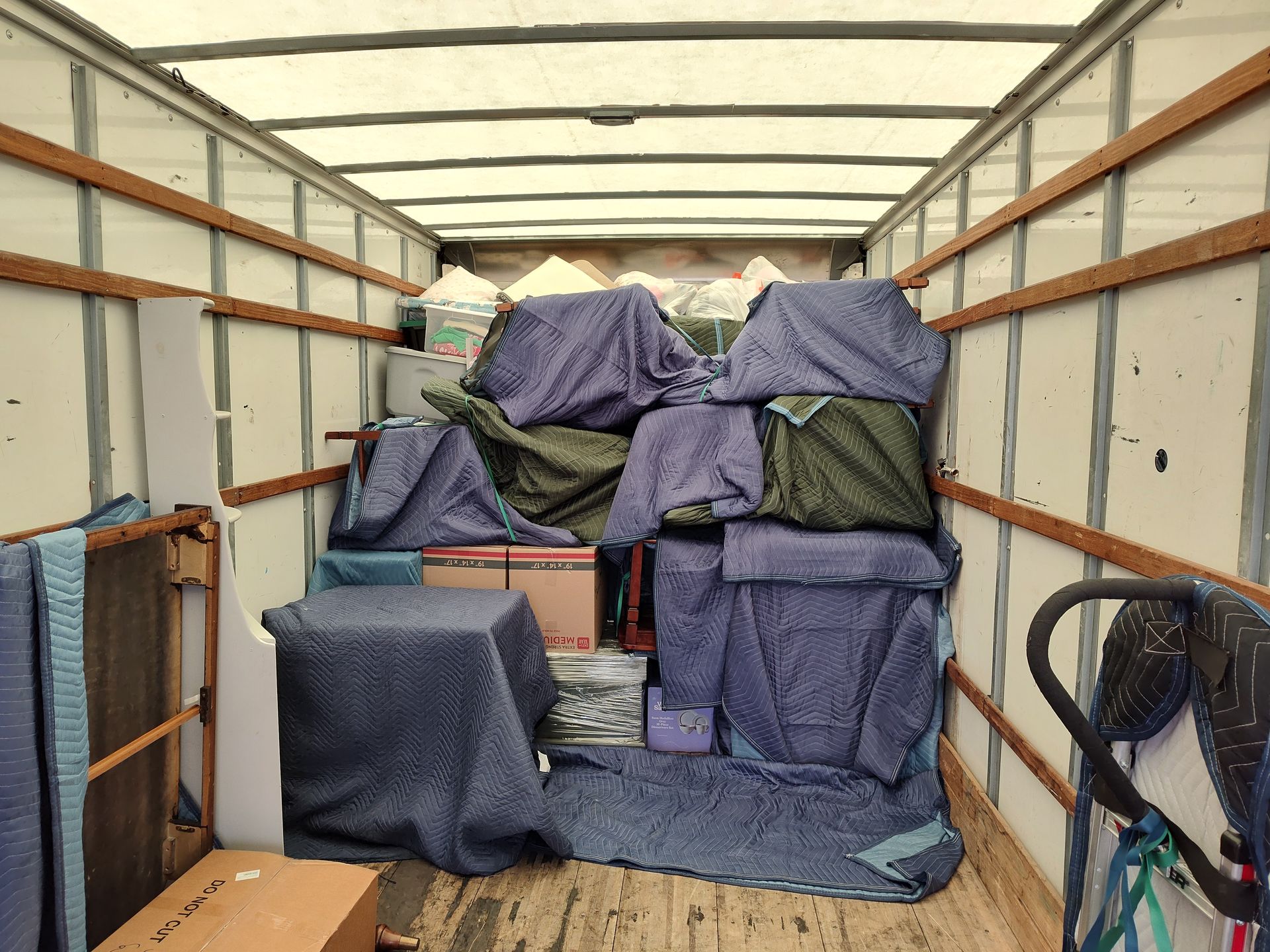 Truck trailer loaded with furniture wrapped in blue and gray blankets for moving