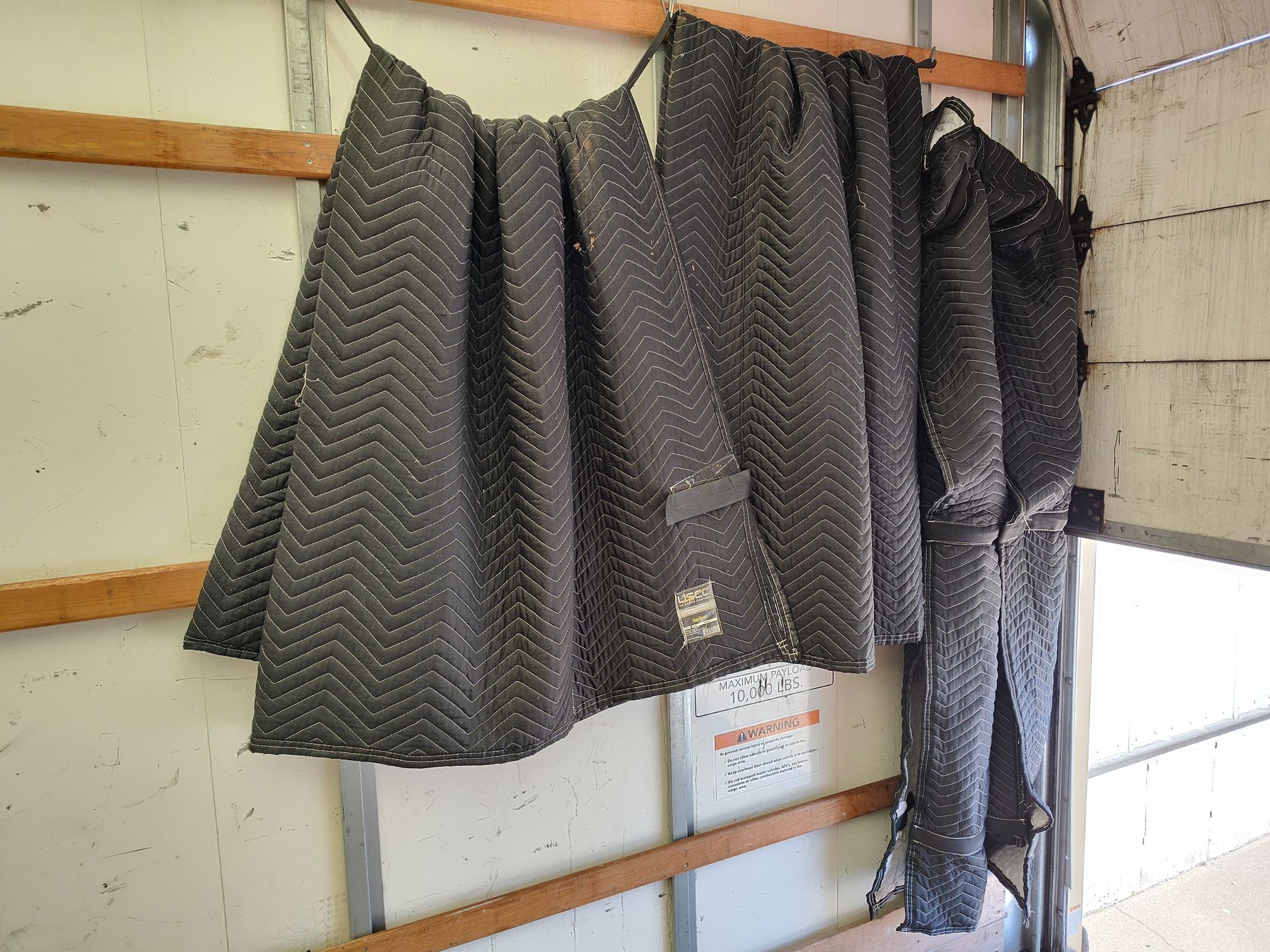 Several dark jackets hang on hooks against a wall in a storage or workroom.