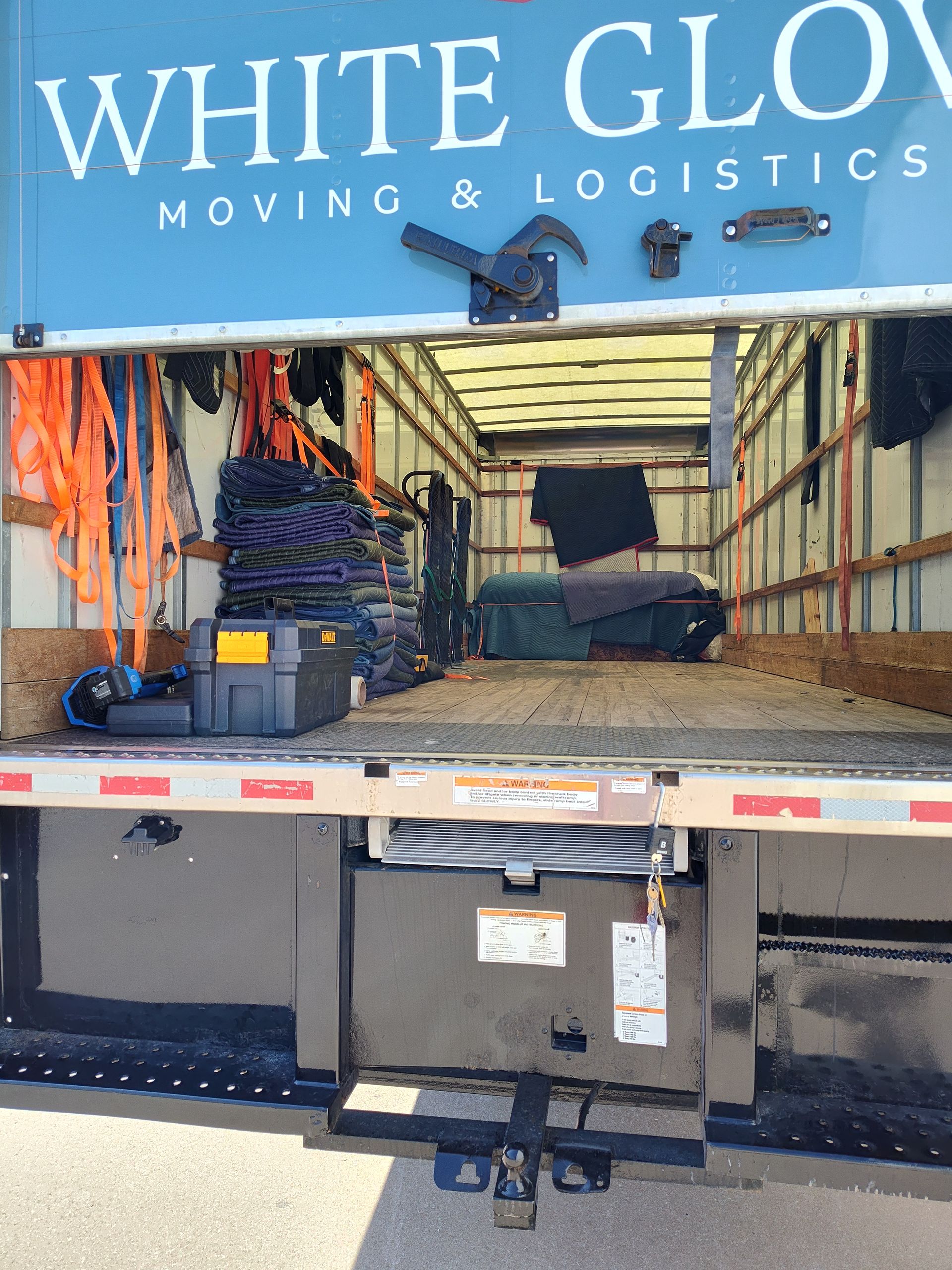 Moving truck loaded with boxes and furniture under a White Glove Moving & Logistics sign
