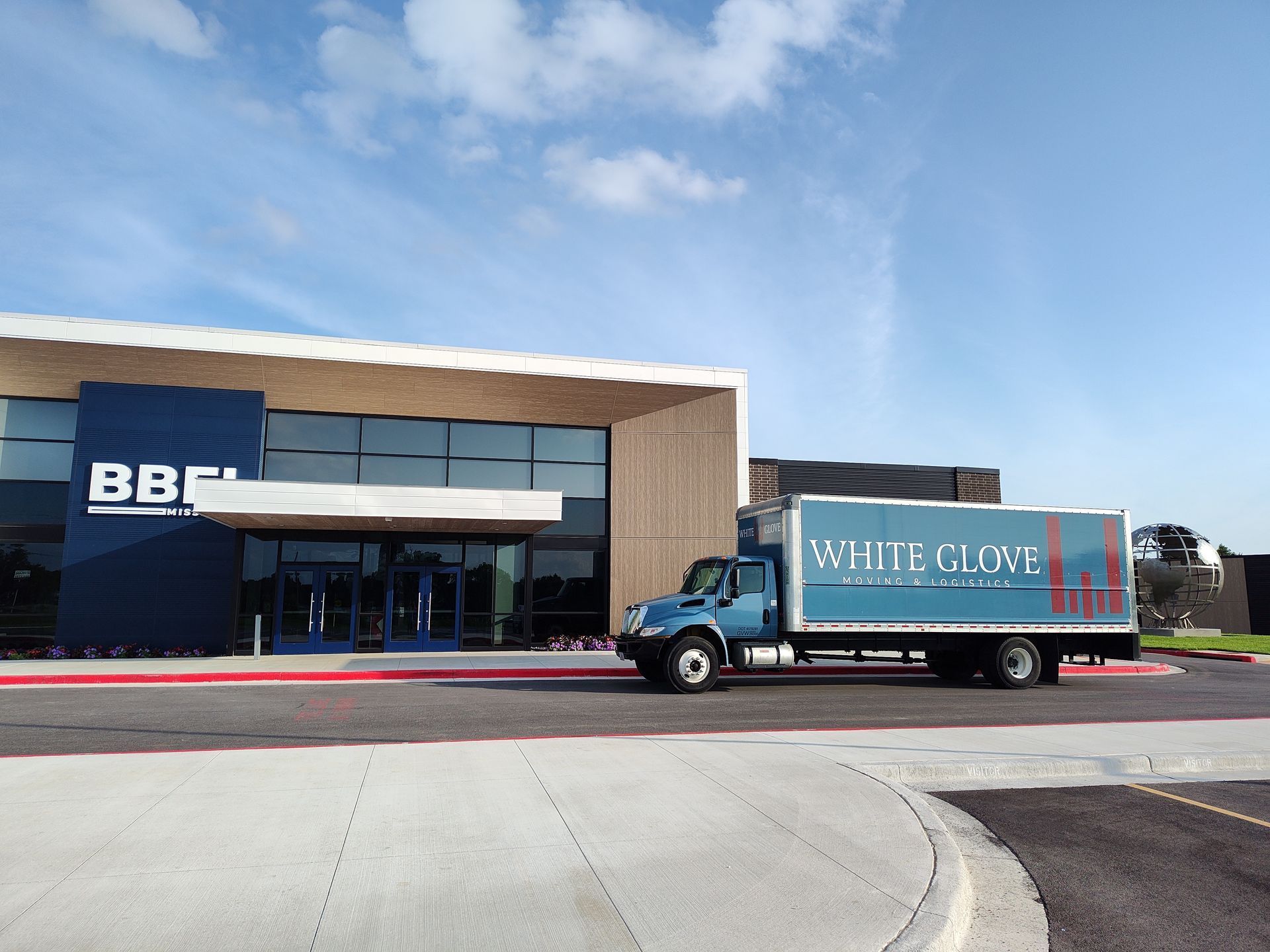 BBI storefront with a White Glove delivery truck parked outside on a sunny day