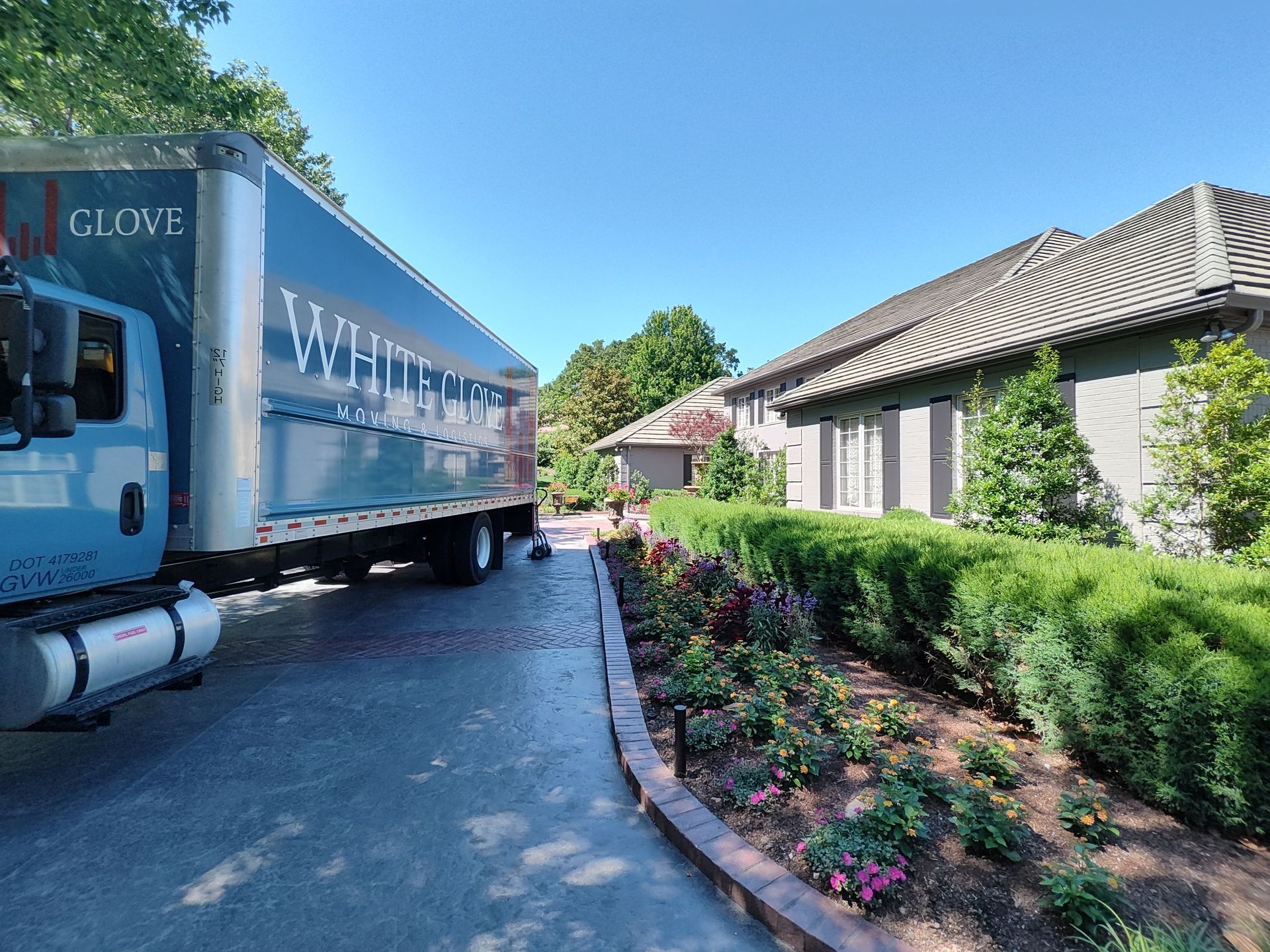 Blue moving truck parked beside a landscaped building under a clear sky