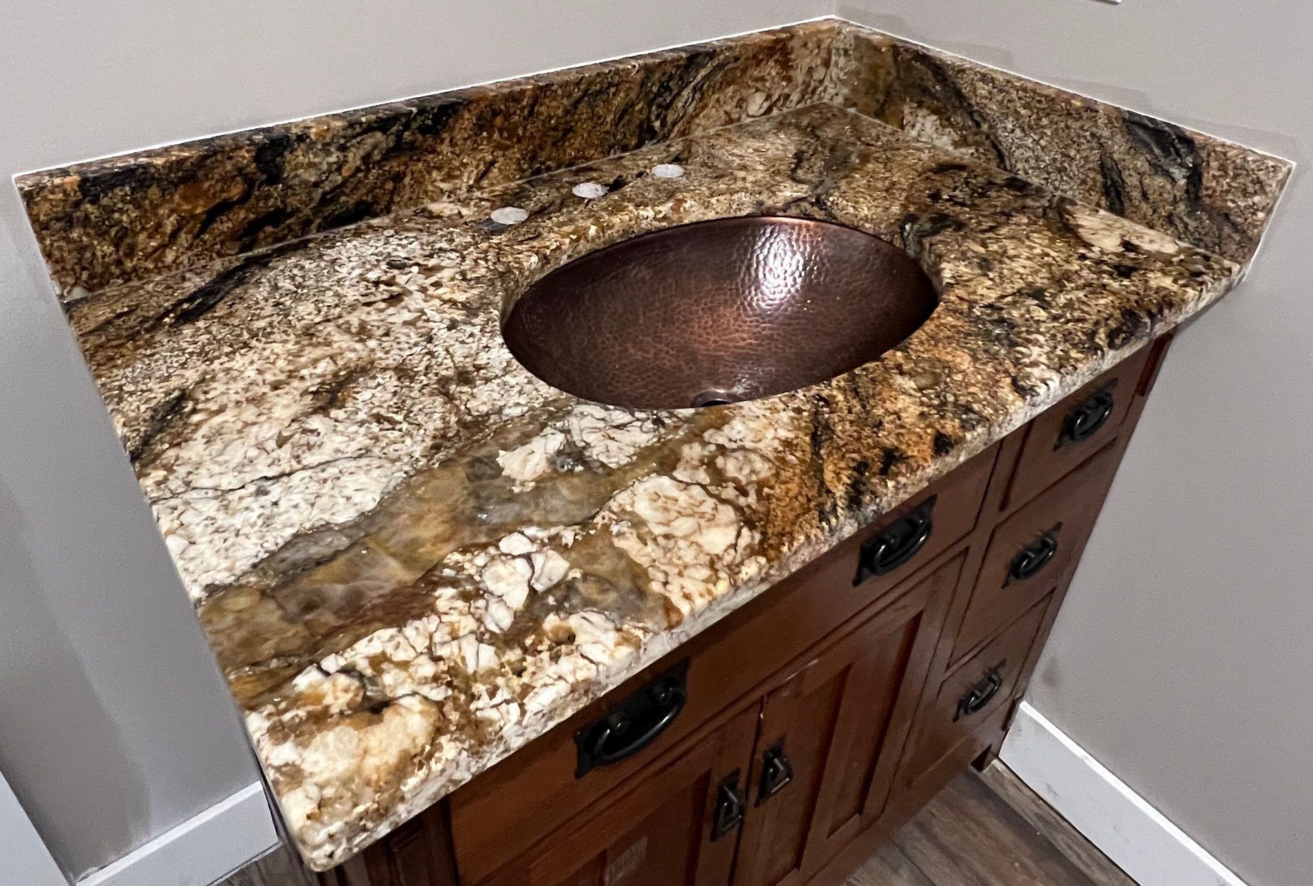 Bathroom vanity with granite countertop and copper sink.