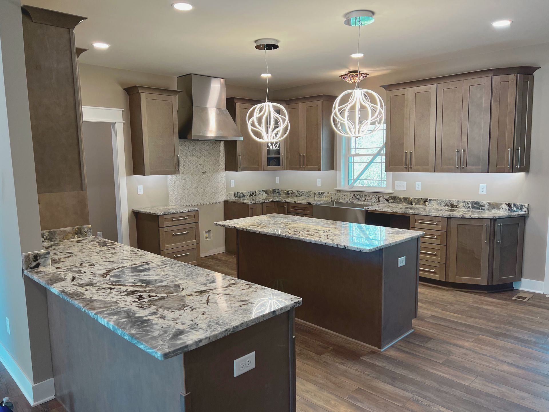 Modern kitchen with brown cabinets, granite countertops, and two islands.