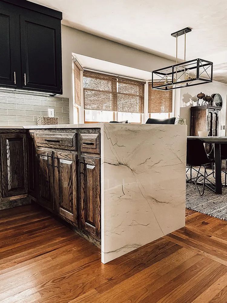 Kitchen with wooden cabinets, a light stone island, and a dining table.