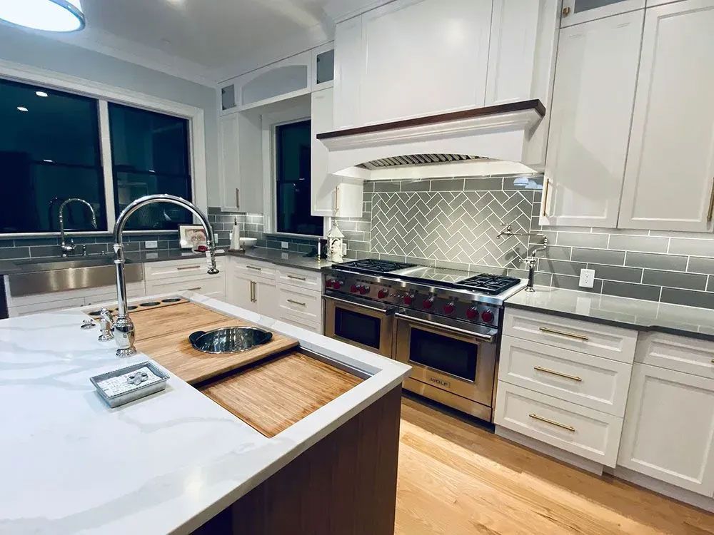 Modern white kitchen with island, stainless steel appliances, and wood flooring