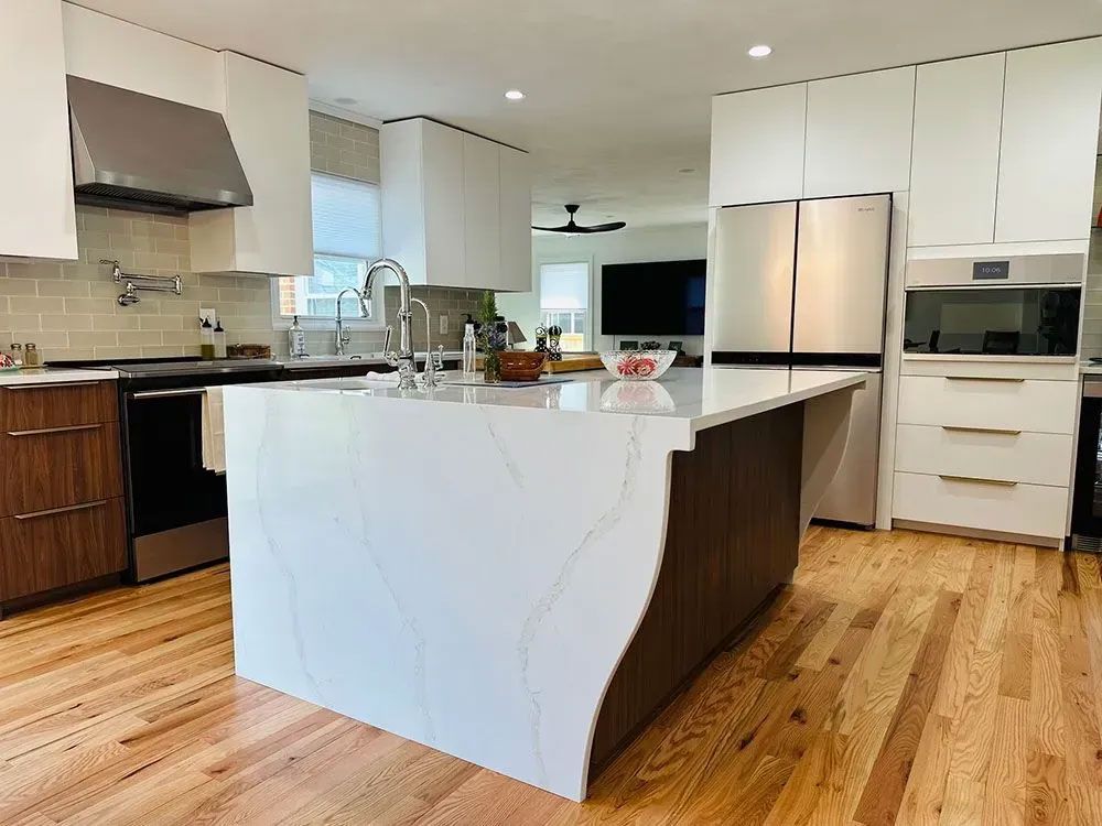 Modern kitchen with white island, stainless steel appliances, dark wood cabinets, and hardwood floors