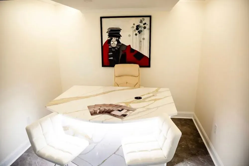 Office space with marble desk, beige chairs, and artwork of a person in red.