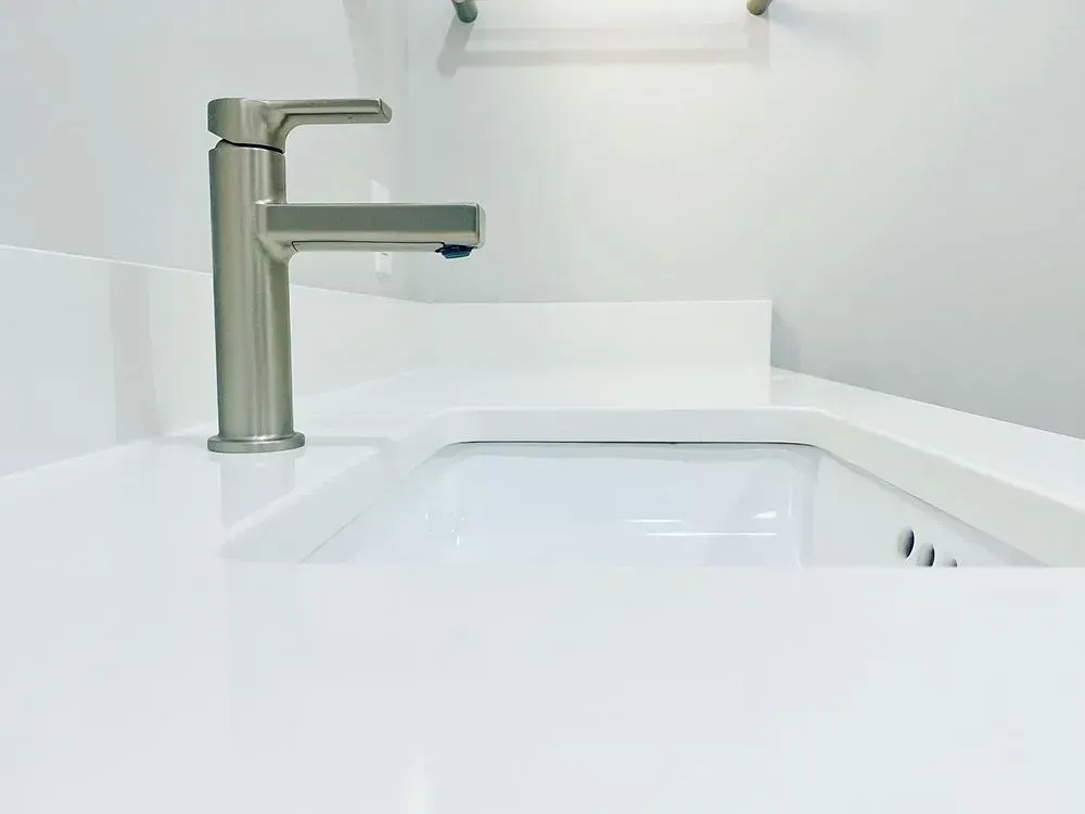 Close-up of a modern bathroom sink with a silver faucet on a white countertop.