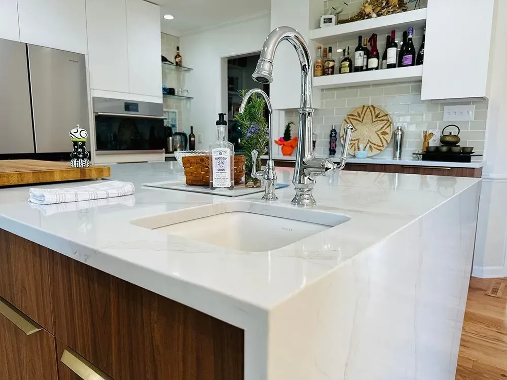 Modern kitchen with white countertops, wooden cabinets, and a stainless steel faucet.