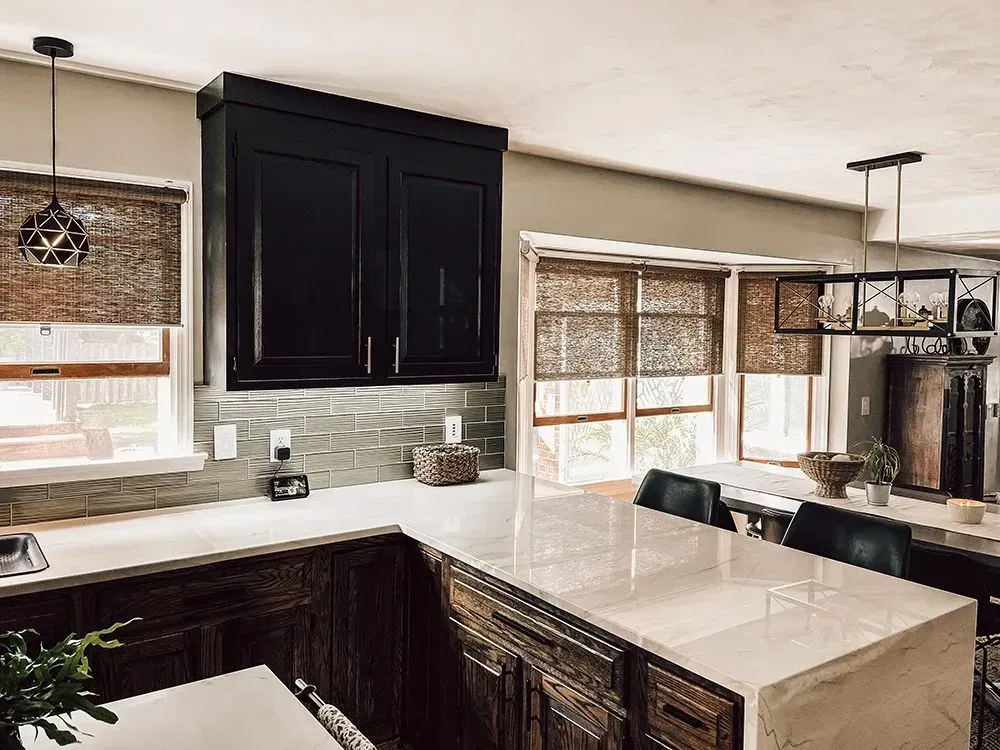 Kitchen with dark cabinets, light countertops, and woven blinds.
