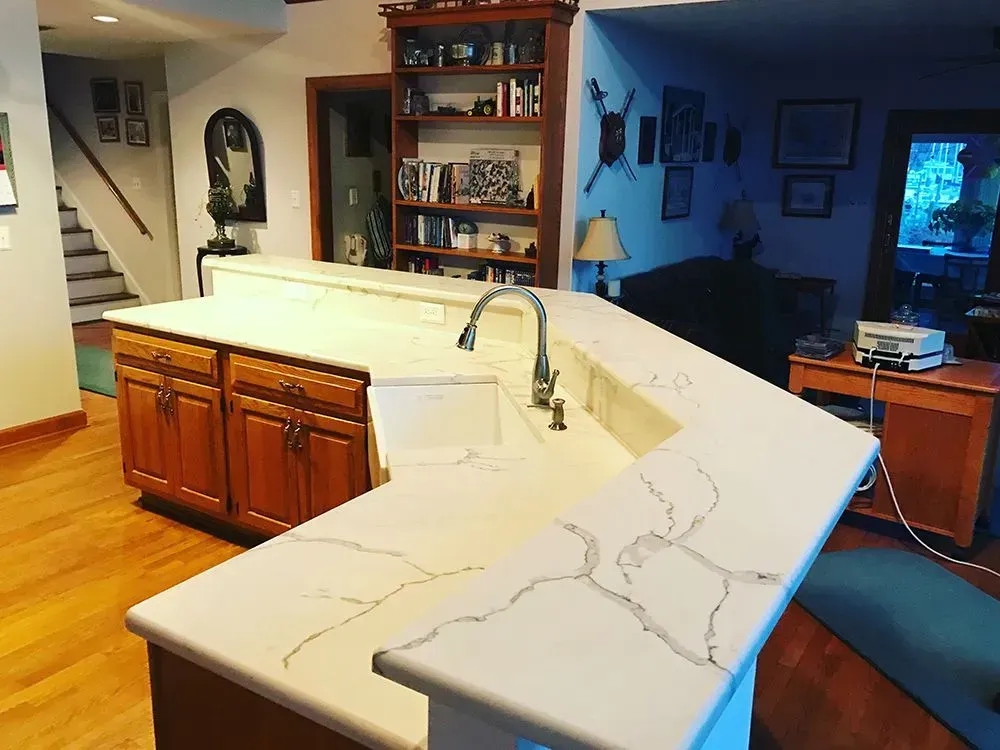 Kitchen with light countertops, wood cabinets, and built-in bookshelf.