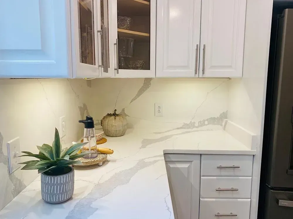White kitchen countertop with cabinets, under-cabinet lighting, and a few decorative items.