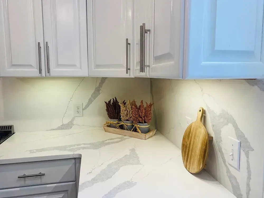 White kitchen with cabinets, countertop, cutting board, and decorative dried plants.