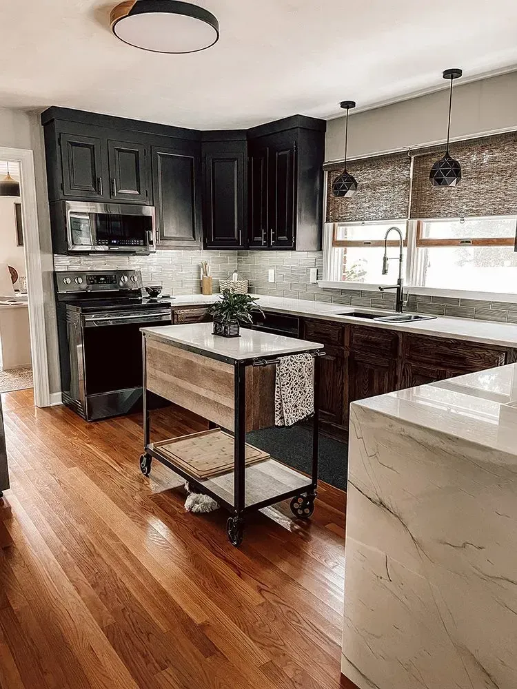 Kitchen with dark cabinets, a white island, and wood floors.