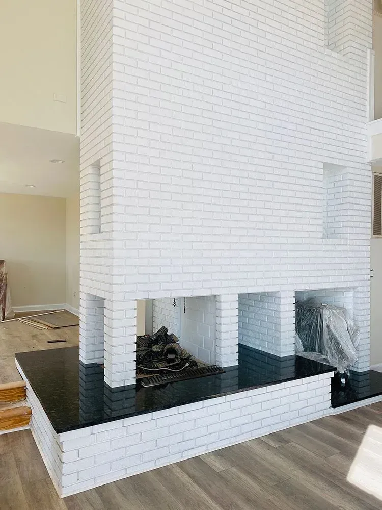 White brick fireplace with black hearth, built into a wall.