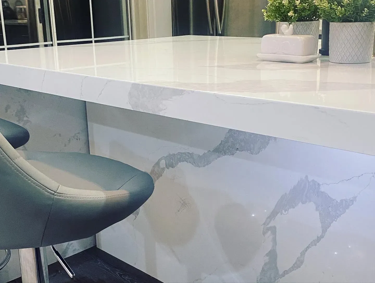 Bar area with white countertop, grey and white patterned backsplash, and a grey bar stool.