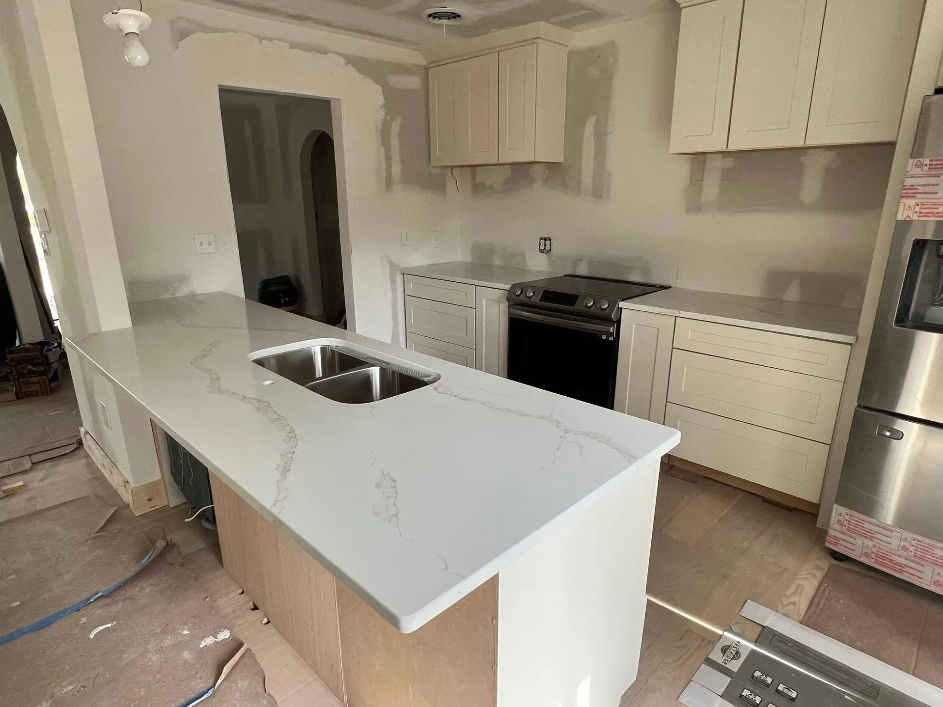Kitchen under construction with white cabinets, countertops, and appliances.