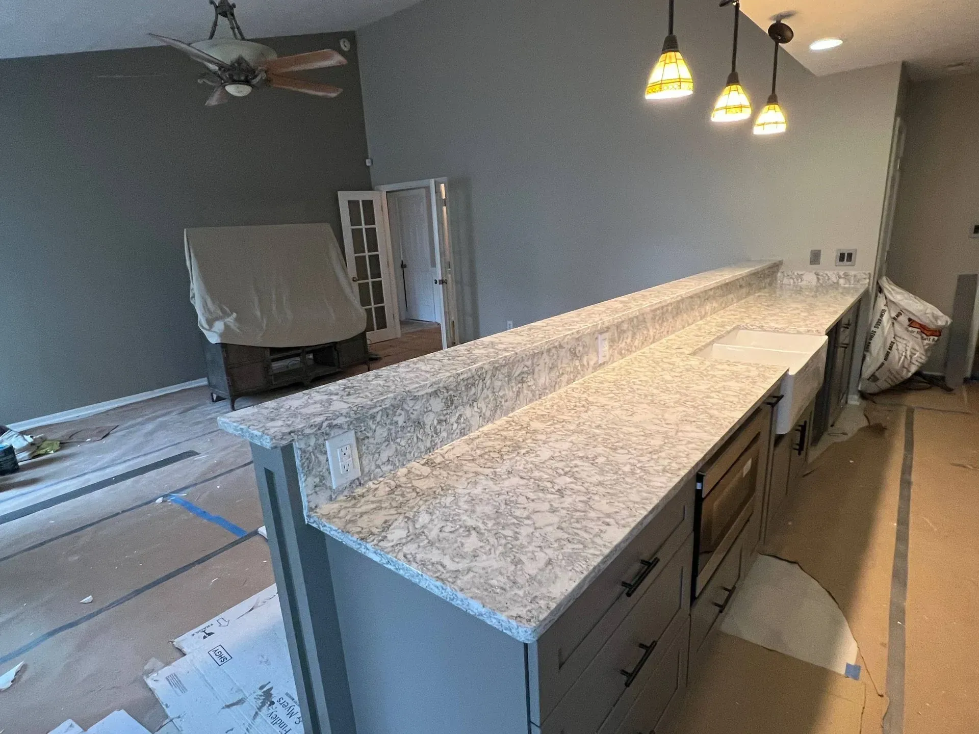 Kitchen island with light gray granite countertop and gray cabinets.