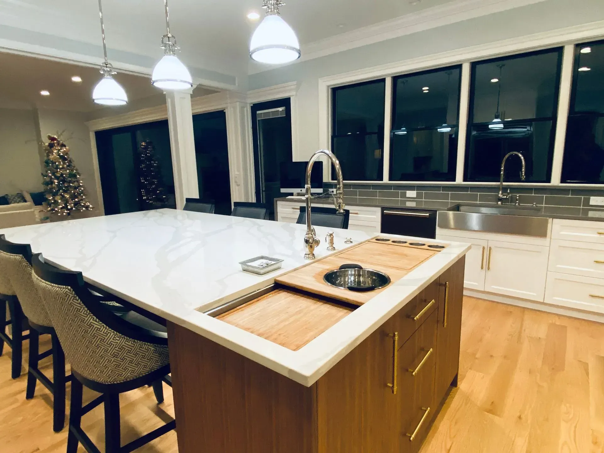 Modern kitchen with large island, seating, white countertops, wood cabinetry, and stainless steel sink.
