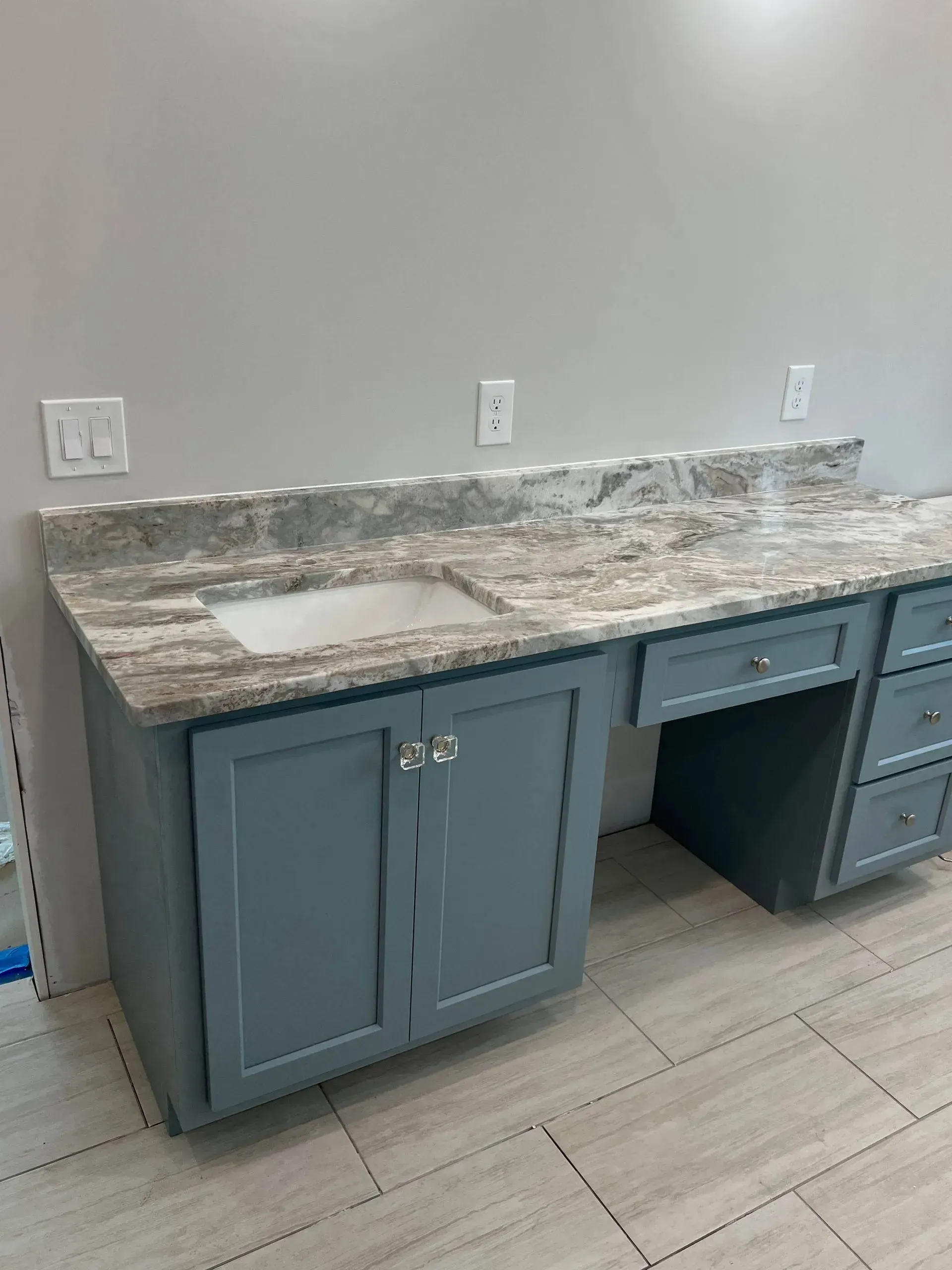 Gray and blue bathroom vanity with granite countertop and drawers.