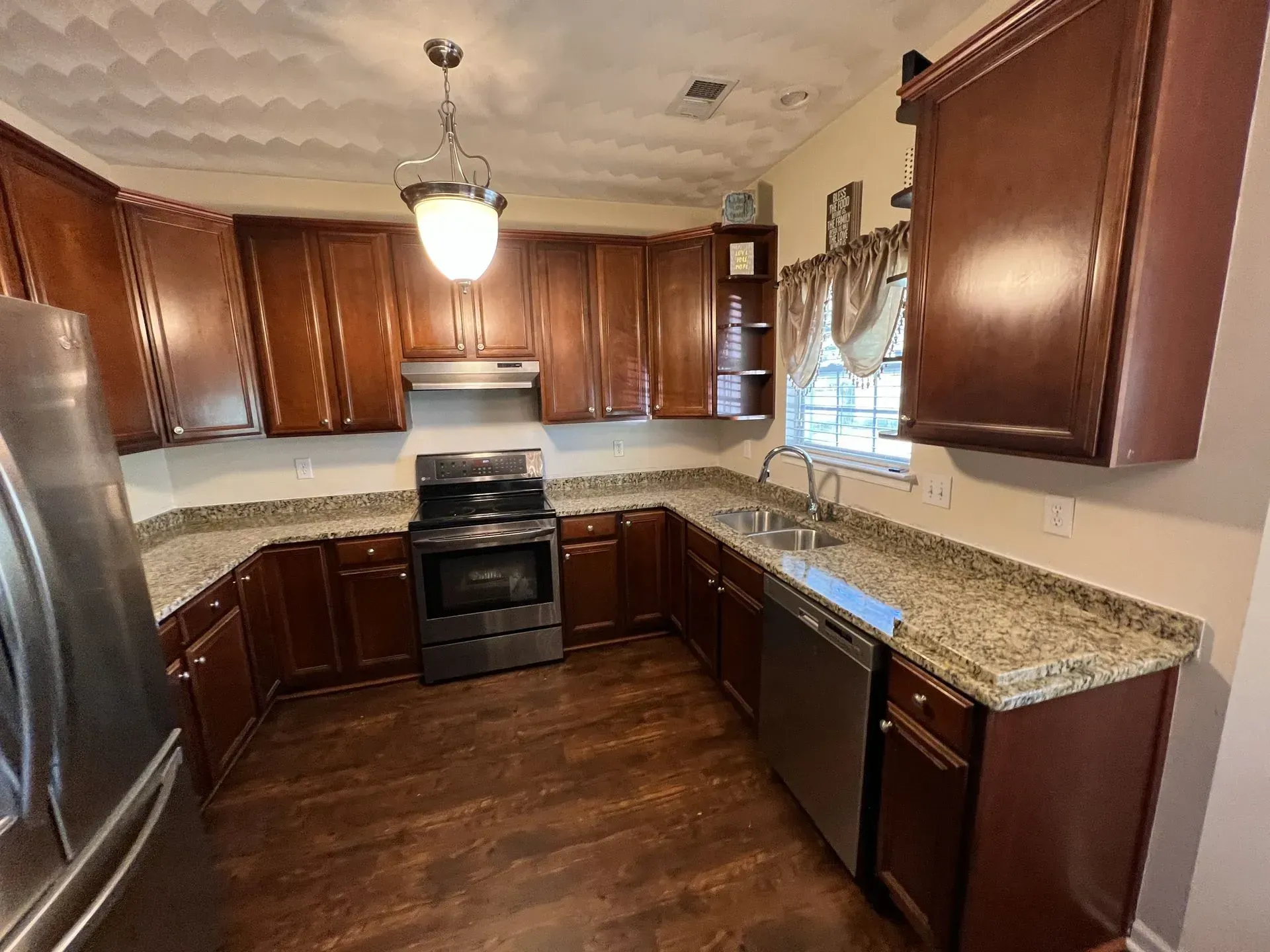 Brown kitchen cabinets with stainless steel appliances and granite countertops.