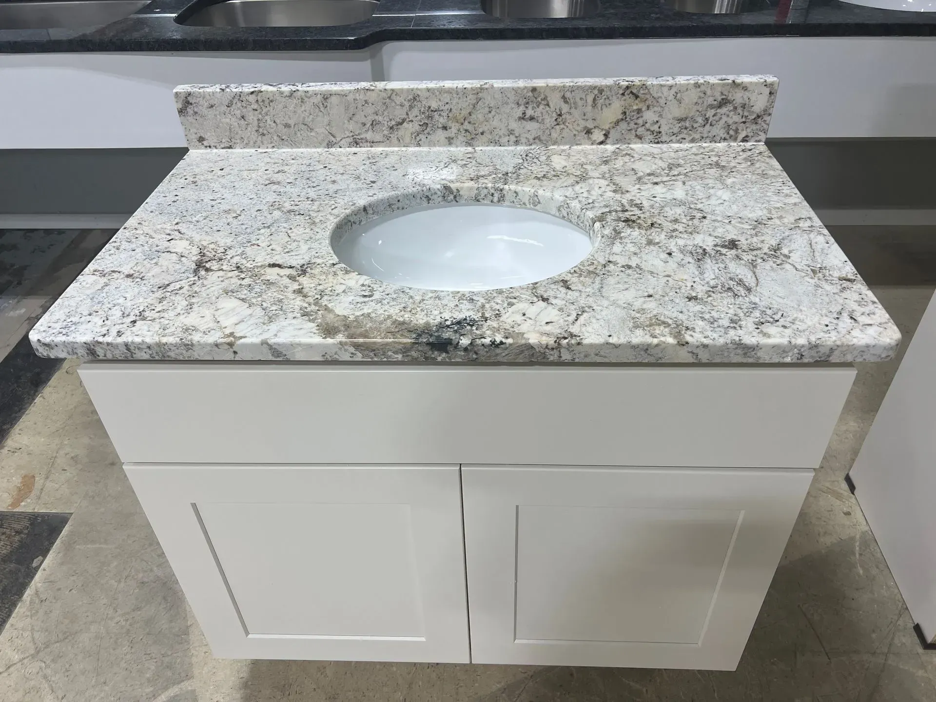 White bathroom vanity with granite countertop and round sink.