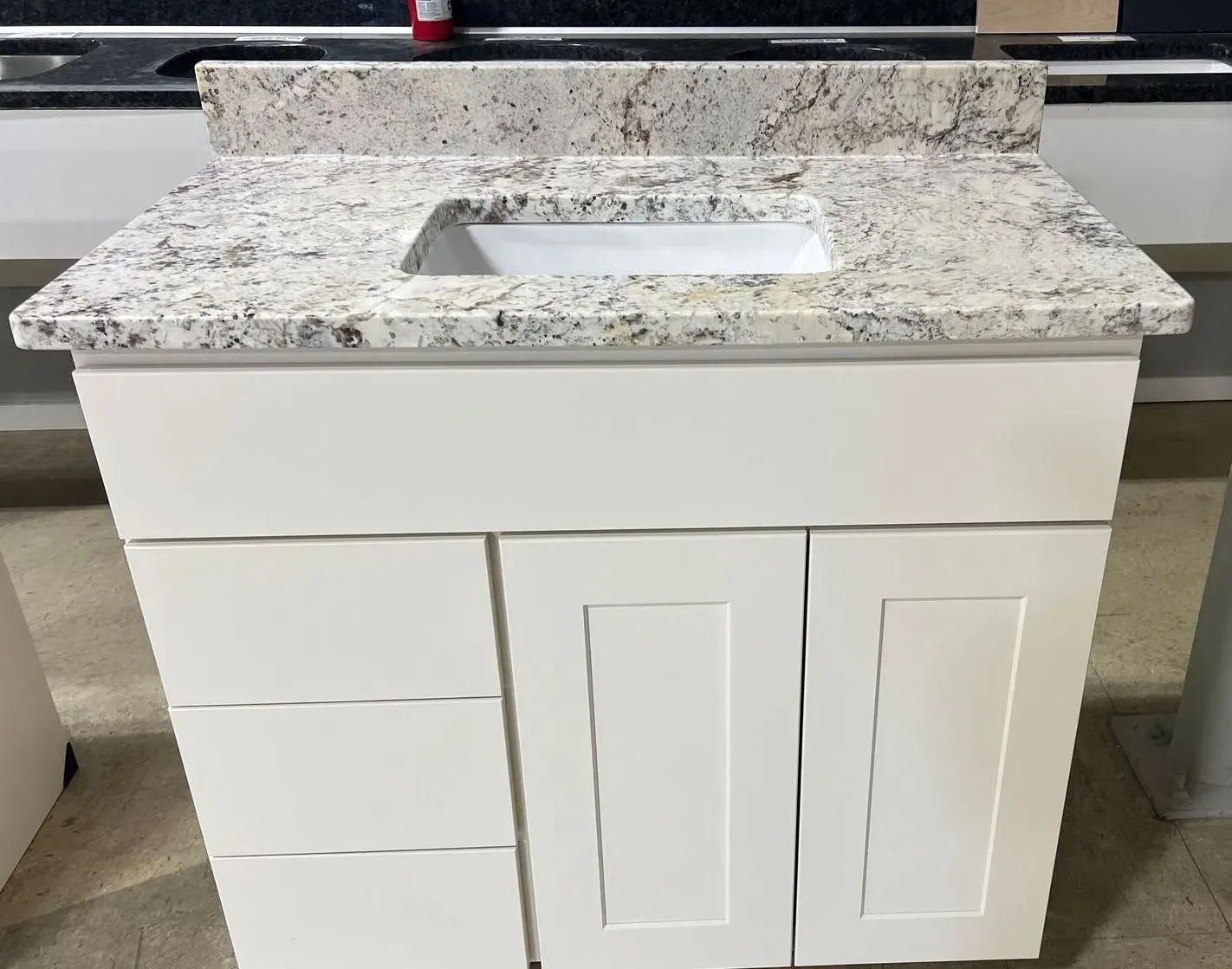 White bathroom vanity with granite countertop and rectangular sink.