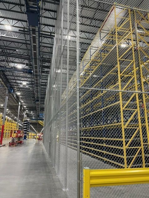 A warehouse with lots of shelves and a chain link fence