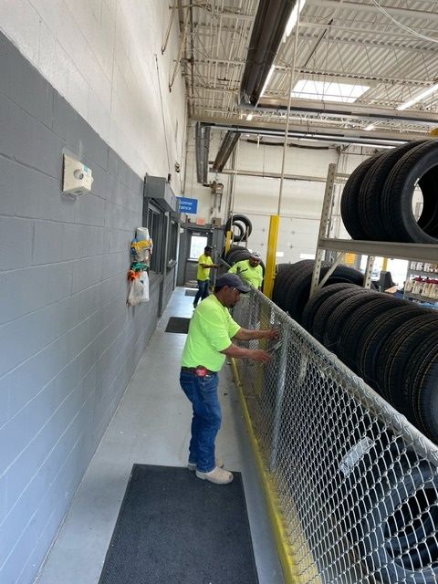 A man in a yellow shirt is working on a chain link fence