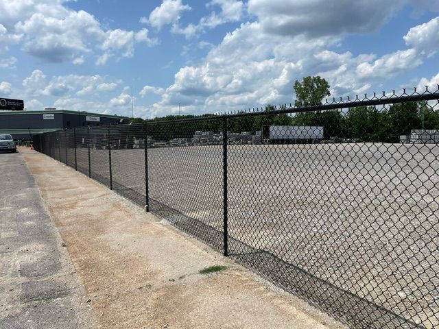 A chain link fence surrounds a large empty parking lot.