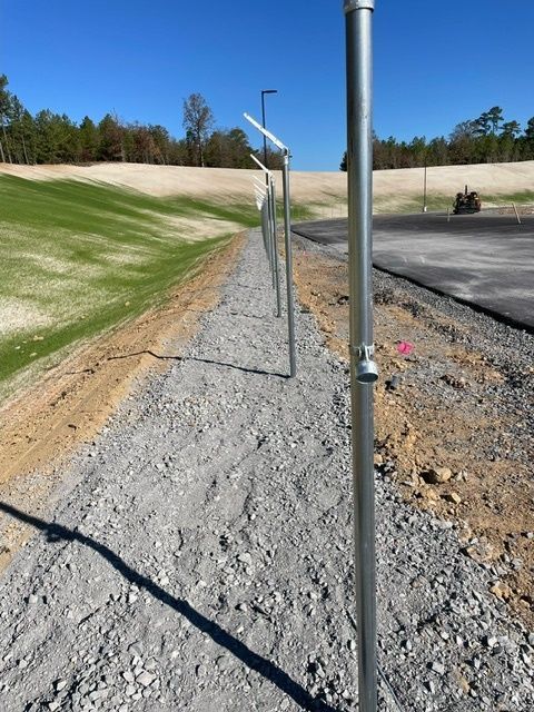 A fence is being built in the dirt near a golf course