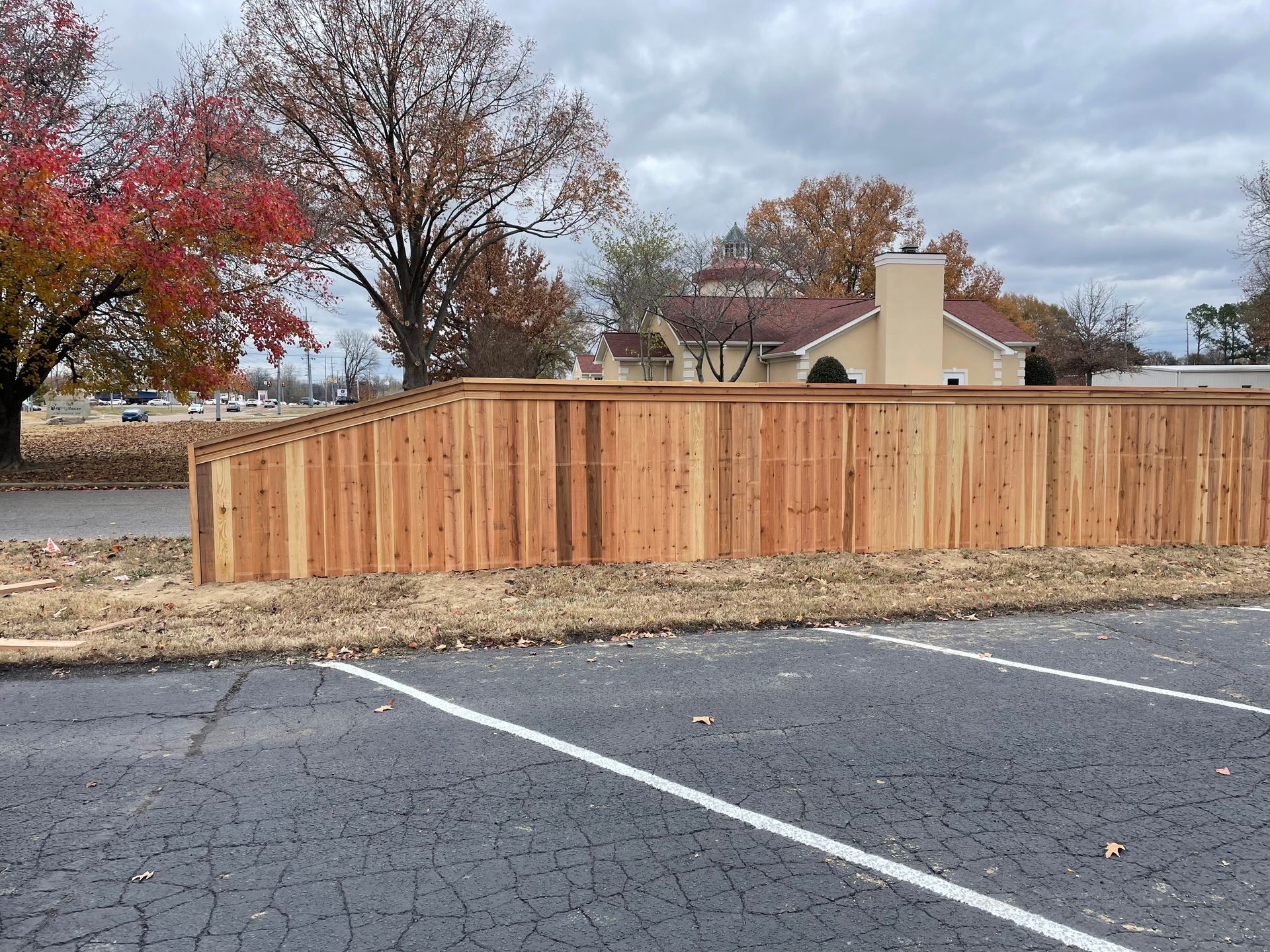 A wooden fence is being built in a parking lot in front of a house.