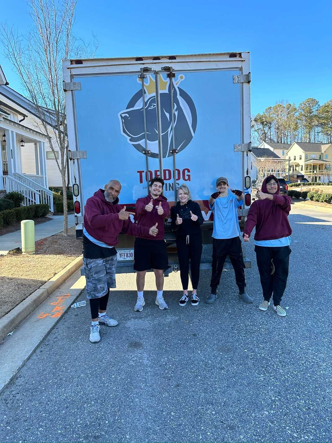 A group of people are standing in front of a moving truck.
