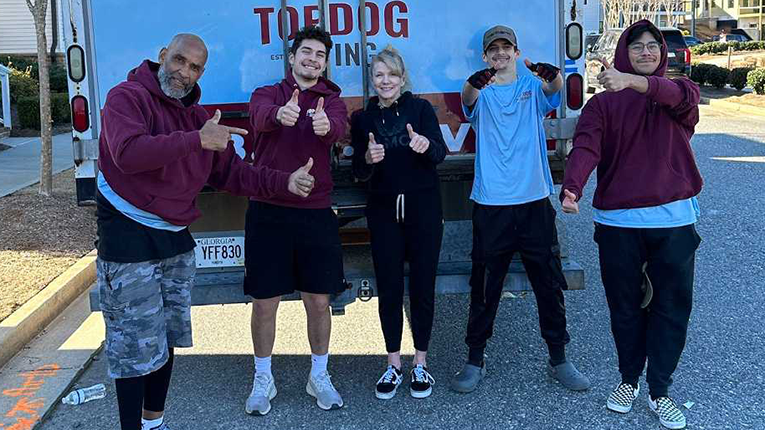 A group of people are standing in front of a truck giving a thumbs up.